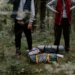 Ultralight foldable camping seat cushion beside hiking backpack on forest campsite ground
