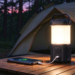 Portable rechargeable camping lantern charging smartphone on wooden campsite table, tent background